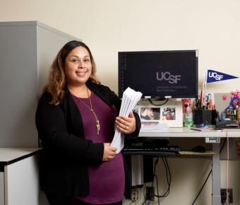 Woman of color standing in front of a computer with "UCSF" on the desktop